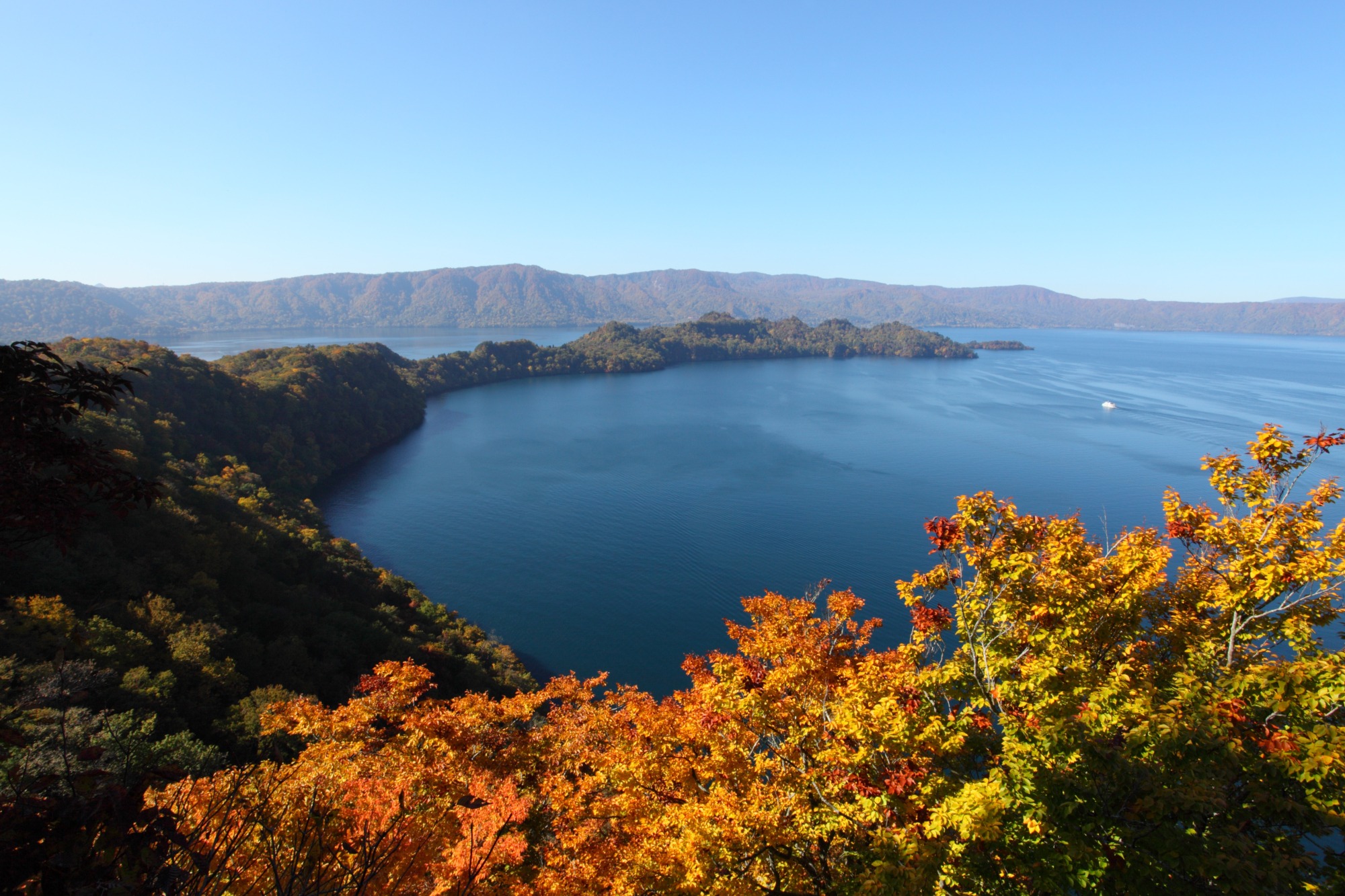 美しい藍をたたえた神秘の湖 空も山々も鏡のように映しこむ